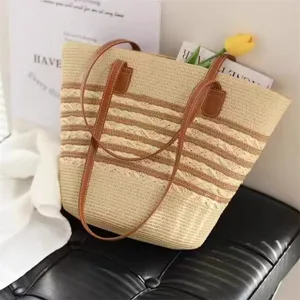 Borsa tote in paglia estiva con manici in pelle marrone e design a righe per la spiaggia.