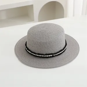 Detalle de un sombrero de paja gris con cinta negra y perlas para los días soleados.