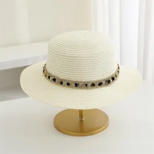 Vista detallada de un elegante sombrero de paja de copa plana con cinta tejida metálica.