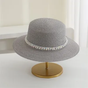 Detailansicht grauer Strohhut mit Perlen und buntem Band, ideal fur Sommerurlaub am Strand.
