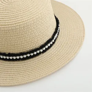 Vista detallada de un elegante sombrero de paja para mujer con cinta de perlas negras.