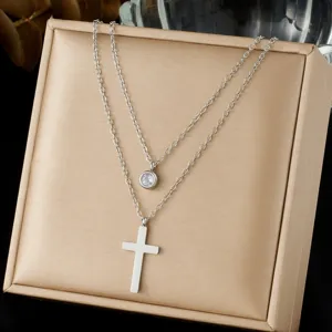 Detail shot of a double-layer silver stainless steel necklace with cross and round pendants.