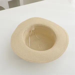 Vista detallada del interior del sombrero de paja beige con banda para el sudor y cinta ajustable.