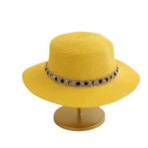 Sombrero de paja plano para mujer con elegante cinta decorativa negro y oro para playa de verano.