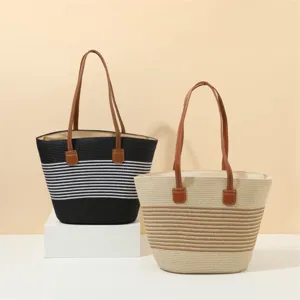 Detailed view of large capacity straw tote bags with stripes and brown leather handles.