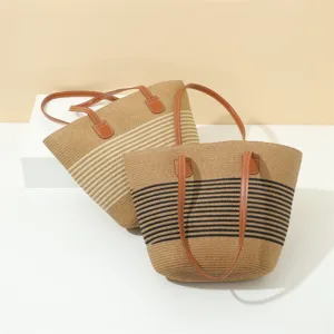 Straw woven tote bag detail showing fine texture, durable PU handles and classic stripe pattern.