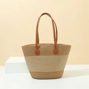 Close-up detail of the straw woven beach tote bag featuring brown leather handles and stripes.