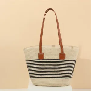 Detail shot of the stylish straw tote bag with black stripes and brown leather shoulder straps.
