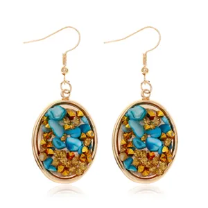 Primer plano detallado de pendientes colgantes dorados con piedras azules y cristales.