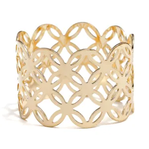 Gold metal napkin ring with openwork geometric pattern for elegant dining table decor.