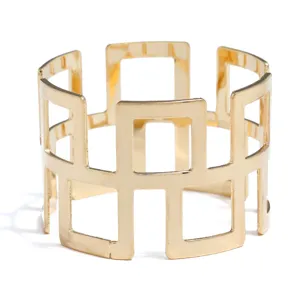 Close-up detail of the gold metal geometric napkin ring featuring an intricate hollow cutout design.