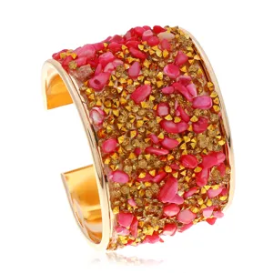 Detalle de brazalete dorado con piedras rosas y tachuelas doradas, diseño muy audaz.