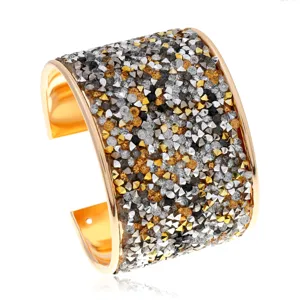 Primer plano detallado de una pulsera brazalete dorada ancha con cristales brillantes.
