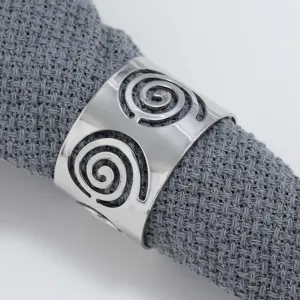 Silver metal napkin ring with hollow spiral design, detail view of modern table decor.