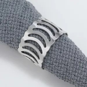 Silver metal hollow napkin ring detail showcasing intricate arch cutouts on a grey fabric.