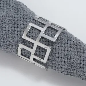 Close-up of hollow geometric metal napkin ring on textured grey fabric, table decor detail.