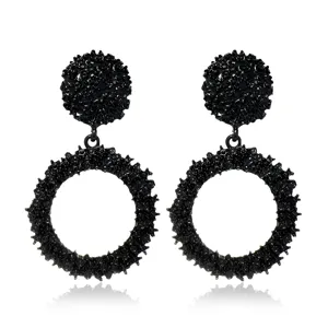 Primer plano detallado de pendientes negros texturizados con diseño de metal fundido único.