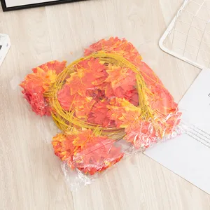 Detailed shot of artificial red maple leaf vine in transparent packaging, autumn decor item.