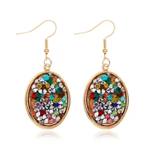 Primer plano detallado de pendientes ovalados de colores con un elegante gancho dorado.