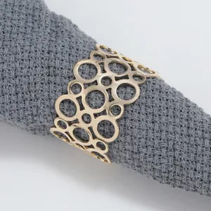 Gold metal hollow napkin ring detail shot, elegant geometric circular design for table decor.