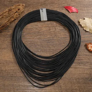 Vista detallada del collar statement de cordón de cuero negro multicapa con cierre magnético.