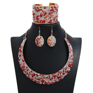 Vista detallada del conjunto de joyas con piedras rojas y pedrería plateada acabado dorado.