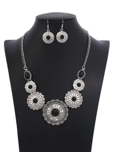 Detailed view of vintage style floral necklace and matching earrings set with black stones.