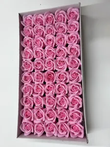 Détail rapproché de têtes de roses en savon artificiel rose rangées dans une boîte cadeau.
