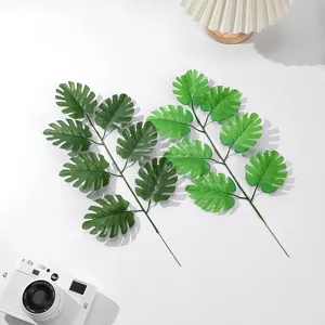 Detail view of artificial monstera leaves branch, green plant for home decor and floral arrangement.