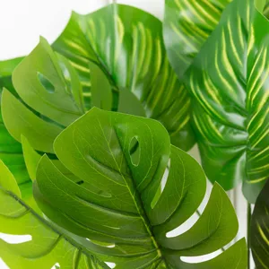 Gros plan de feuilles de monstera artificielles à texture réaliste, idéales pour déco.