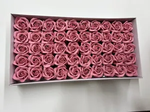 Vue de détail de têtes de roses en savon artificiel rose, rangées dans une boîte pour la décoration.