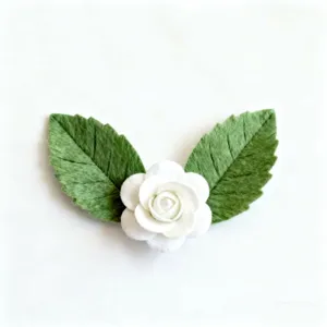 Vue détaillée d'un camélia blanc en tissu, feuilles vertes délicates, accessoire DIY.
