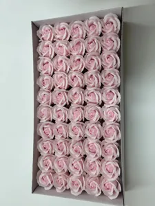 Gros plan de têtes de roses en savon artificiel rose, disposées soigneusement dans une boîte.