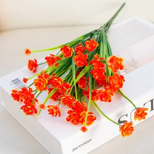 Gros plan détaillé d'un bouquet de fleurs artificielles orange sur un livre décoratif.