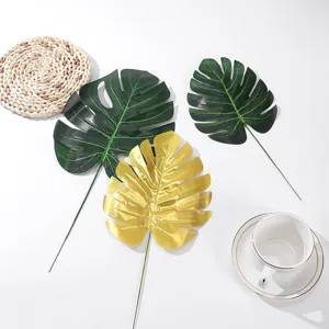 Artificial monstera leaf detail shot, gold and green decorative floral arrangement prop.