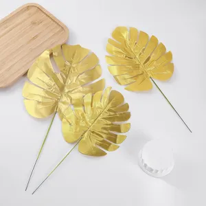 Detail shot of artificial gold monstera leaf with stem, perfect for wedding floral decor props.