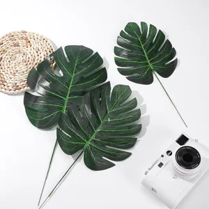 Artificial monstera leaf flat lay detail, green plant photography prop, home decor floral arrangement.