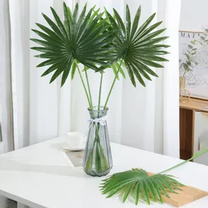 Close up detail of artificial fan palm leaves in a glass vase, elegant green home decor.