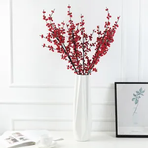 Detail view of artificial red berry branches in a white vase for festive home decoration.