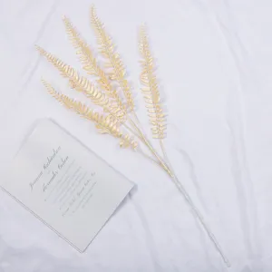 Artificial gold fern plant leaf branch detail shot for wedding floral arrangement decor.
