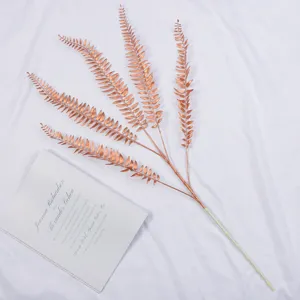 Close-up detail of artificial copper fern leaves, premium plastic wedding floral branch decor.