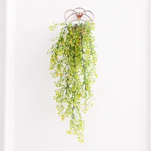 Artificial green plant wall hanging detail, cascading vines in wire basket for home.