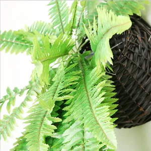 Detailed close-up shot of artificial Boston fern hanging in a woven basket wall decor.