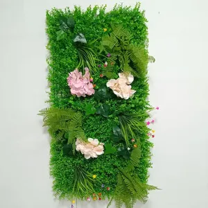 Dettaglio pannello parete vegetale finta, foglie verdi rigogliose e fiori per decoro.