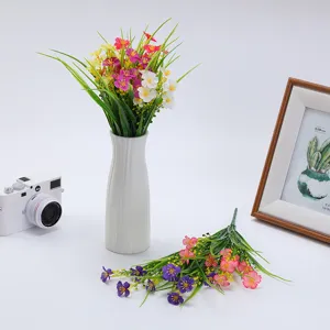 Artificial flower bouquet scene detail, colorful small daisies and spring grass home decor display.
