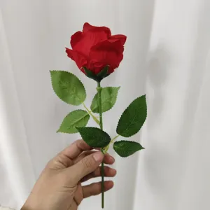 Artificial red rose detail shot showing vivid petals, green leaves and stem structure for decor.