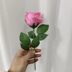 Detail view of a pink artificial rose flower with green leaves, perfect for indoor home decor.