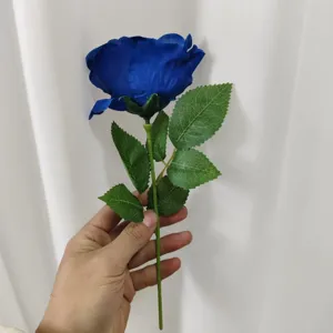 Close-up detailed view of a vibrant artificial blue rose featuring realistic green leaves and stem.