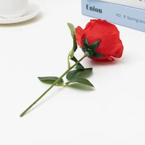 Artificial single red rose detail shot, realistic flower head with green stem for home decor.