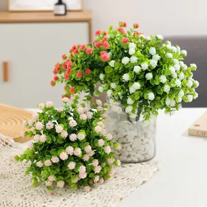 Arrangement de fleurs artificielles d'eucalyptus camélia avec vase en verre et pierres.